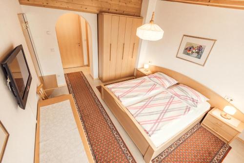 a small bedroom with a bed and a tv at Gass-Hof in Caldaro