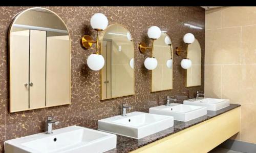 a bathroom with three sinks and two mirrors at Onelakeshore back smx lanang in Davao City