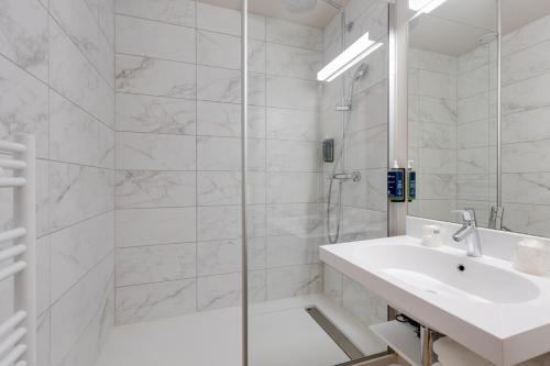 a white bathroom with a sink and a shower at Karaez Hôtel - BritHotel Carhaix in Carhaix-Plouguer