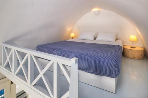 a bedroom with a bed with a blue comforter at VITAMIN STUDIO in Oia
