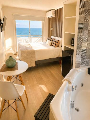 a bedroom with a bed and a tub and a view of the ocean at Dei Templi Hotel in Viña del Mar