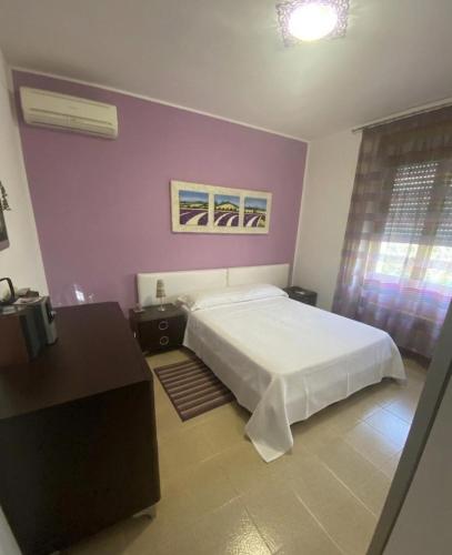 a bedroom with a white bed and a purple wall at La Villetta in Giulianova