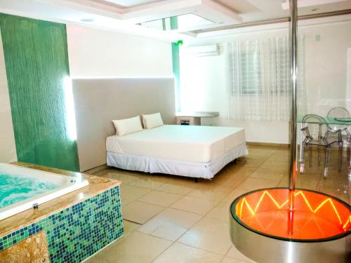 a bedroom with a tub and a bed and a bath room at Alpino Motel by Drops in Jundiaí