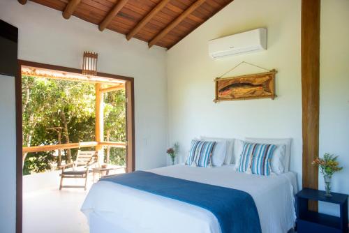 a white bedroom with a bed and a patio at Pousada Lua Cheia Praia do Espelho in Praia do Espelho