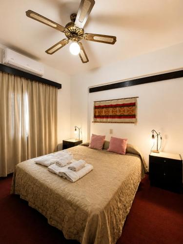 a bedroom with a bed with a ceiling fan at Grand Hotel by MH in Termas de Río Hondo