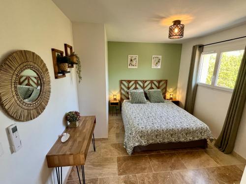 a bedroom with a bed and a mirror and a table at Le Clos de L'Oliveraie - Appartements de charme avec piscine proche d'Uzès in Sagriès