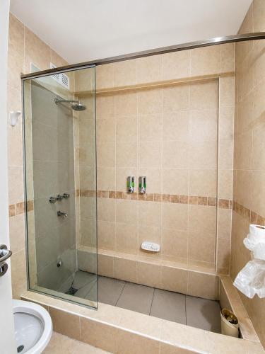 a shower with a glass door in a bathroom at Grand Hotel by MH in Termas de Río Hondo