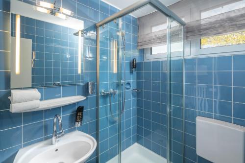a blue tiled bathroom with a sink and a shower at LU8 Business Vital Hotel in Bad Dürrheim