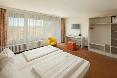 a bedroom with a large white bed and a desk at LU8 Business Vital Hotel in Bad Dürrheim