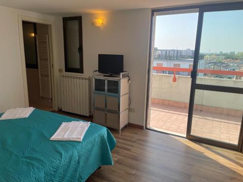 a room with a bed and a tv and a balcony at Apartament 2 bedroom with one bathroom and penthouse Apartament 3 bedroom and 2 bathroom included with umbrella and sunbeds in Lido Adriano