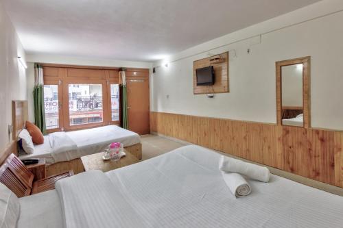 a hotel room with two beds and a television at Hotel Moonlight Manali in Manāli