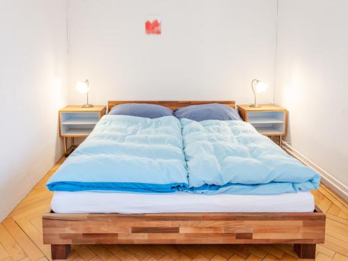 a bed with blue and white sheets and two night stands at La Colonie, former watch factory in Les Pommerats