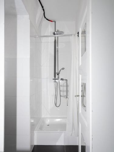 a white bathroom with a shower and a tub at La Colonie, former watch factory in Les Pommerats