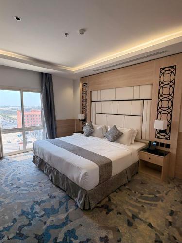 a bedroom with a large bed and a large window at Mora by jodna - فندق مورا in Al Khobar