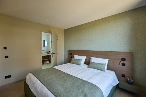 a bedroom with a large bed with white sheets at Vakantiewoning Belle Vue in Hooglede