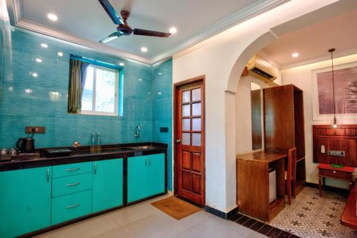 a kitchen with blue cabinets and a sink and a door at Bliss By Stays,Calangute in Calangute