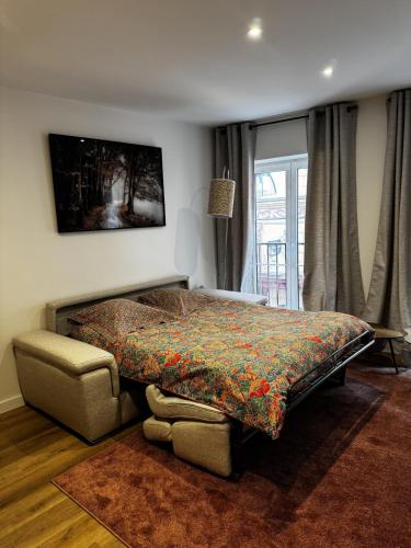 a bedroom with a bed and a chair and a window at Le Chevalier I - L'Écrin Alsacien in Sélestat