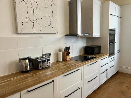 a kitchen with white cabinets and a wooden counter top at High Street Suites 3 in Ventnor