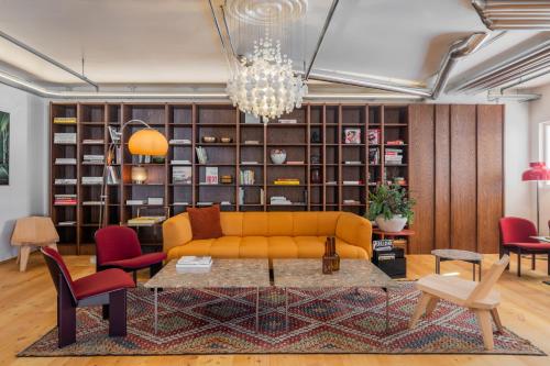 a living room with a yellow couch and red chairs at La Senda Smart Hotel Zuoz in Zuoz