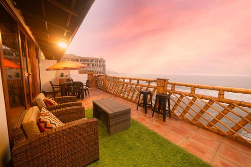 ein Balkon mit Sofas und Tischen und Meerblick in der Unterkunft Hotel Sunset Chancay in Chancay
