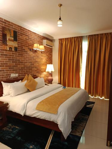a bedroom with a large bed and a brick wall at Grand Hôtel City - Akwa in Douala