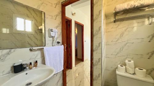 a bathroom with a sink and a toilet and a mirror at Spacious Triplex in Harhoura in El Harhoura