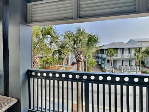 a balcony with a view of palm trees and houses at The Holland House II in Rosemary Beach