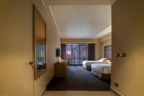ein Hotelzimmer mit zwei Betten und einem Fenster in der Unterkunft Hotel Costanera Concepcion in Concepción