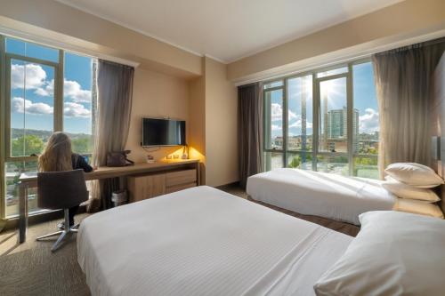 Eine Frau sitzt an einem Schreibtisch in einem Hotelzimmer mit zwei Betten in der Unterkunft Hotel Costanera Concepcion in Concepción