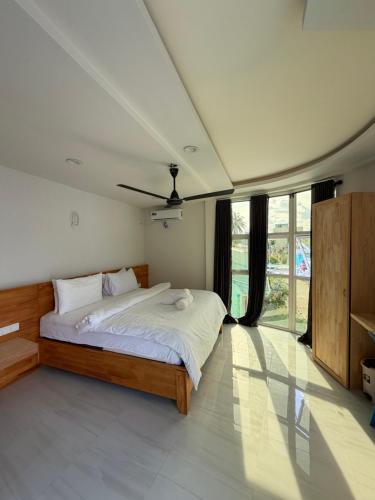 a bedroom with a bed and a large window at Green Villa in Huraa