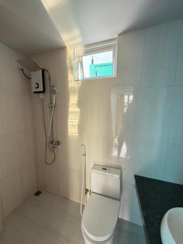 a bathroom with a toilet and a sink and a window at Green Villa in Huraa