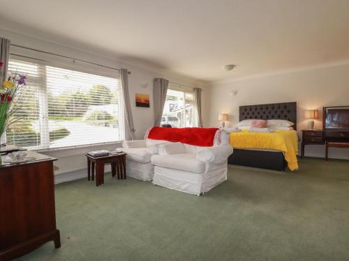 a bedroom with a bed and a couch and a chair at Tregoning Annexe in Lostwithiel