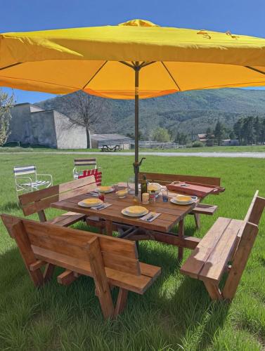 a picnic table with a yellow umbrella and benches at Maison de campagne T3 Nature in La Martre