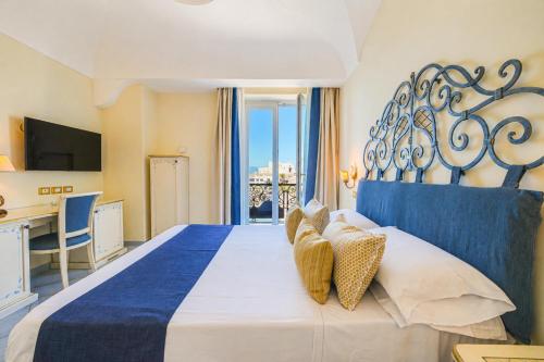 a bedroom with a large bed with a blue headboard at Hotel Nettuno in Forio d'Ischia