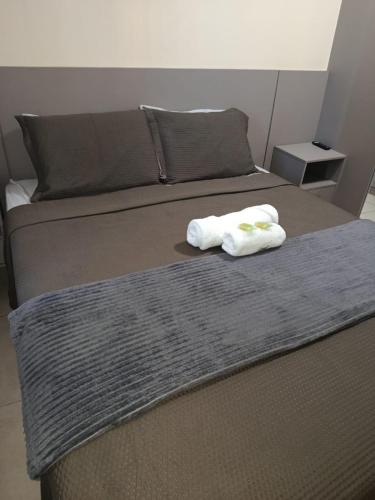 a bed with two towels on top of it at Apartamento 1 km da praia com ar e garagem in Vila Velha