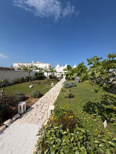 a garden with a stone walkway and flowers on the grass at Trulli sul Mare Forcatella in Savelletri di Fasano