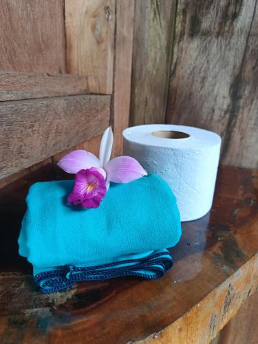 a roll of toilet paper and a purple flower on a towel at Lodge El Amargal - Reserva Natural, Ecoturismo & Surf in Nuquí