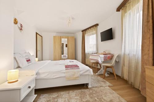 a bedroom with a white bed and a table with a chair at Casa Dava in Râşnov