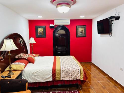 a bedroom with a bed and a red wall at El Tesoro de Arturo in Tilapa