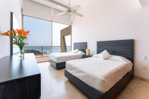 two beds in a bedroom with a view of the ocean at 1083 - Cosmo 3A3 in Tangolunda