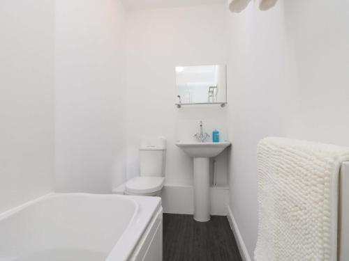 a white bathroom with a sink and a tub and a toilet at Farriers Cottage in Bridlington