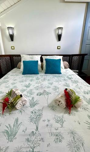 a large bed with blue pillows and flowers on it at Lili bungalows in Capesterre