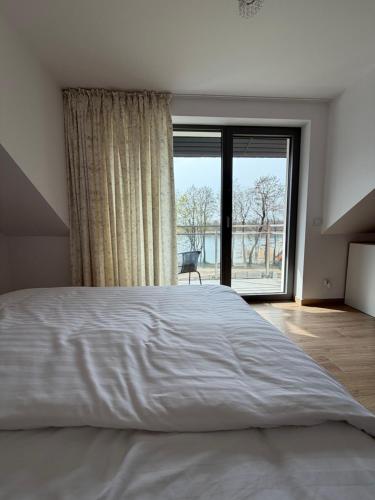 a bedroom with a large bed and a large window at MazuryLive in Węgorzewo