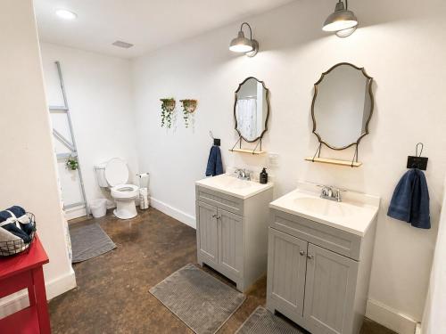 a bathroom with two sinks and a toilet and mirrors at Carriage House in Lufkin