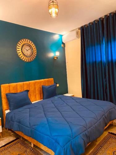 a bedroom with a blue bed with a clock on the wall at Ali City Hotel tunis in Tunis