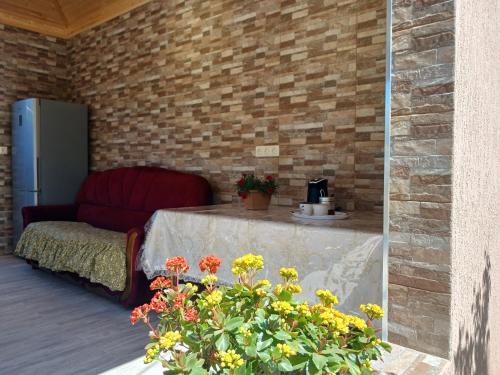 a patio with a table and a couch and flowers at Guest house Nano in Martvili