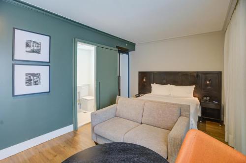a bedroom with a bed and a couch and a chair at Transamerica Executive Perdizes in São Paulo