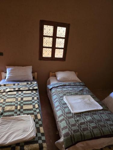 two beds in a room with a window at Dunes Activity Camp in Mhamid
