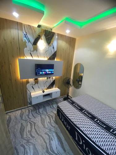 a bedroom with a bed and a tv on a wall at Asika Luxe Living in Ayobo