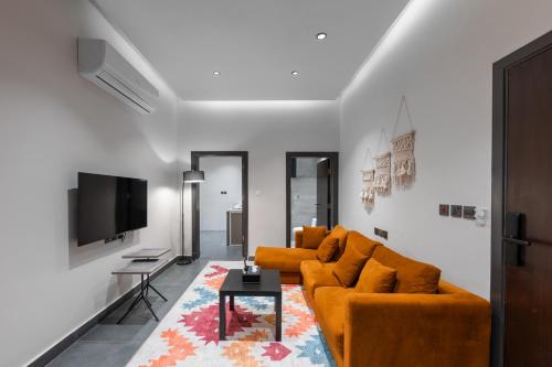 a living room with two orange couches and a tv at الاورفلي للوحدات السكنية in Sulţānah